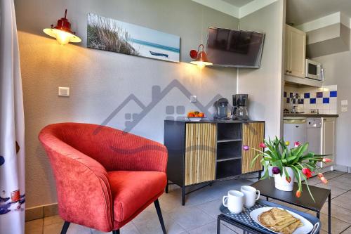 un salon avec une chaise rouge et une table dans l'établissement LocaLise - Maison G5 au Guilvinec - A 50m de la mer avec jardin et piscine - Tout à pied, plages, port, centre, commerces, marché - Wifi inclus - Animaux bienvenus - Linge de lit inclus, au Guilvinec