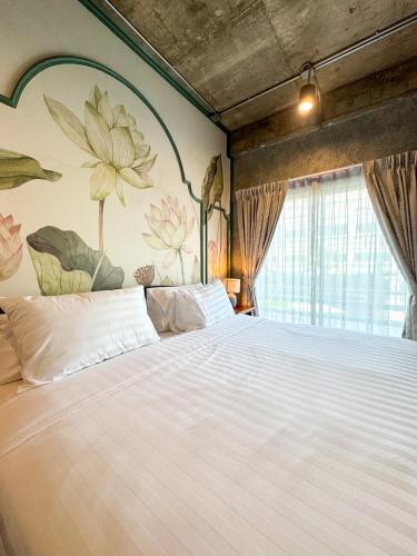a bedroom with a large white bed with a flower mural at Nara Poshtel Sathorn in Bangkok