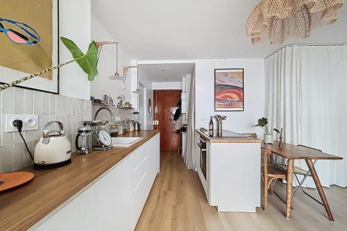 une cuisine avec des armoires blanches et une table en bois dans l'établissement Elegant apartment near Belleville & Jourdain, à Paris