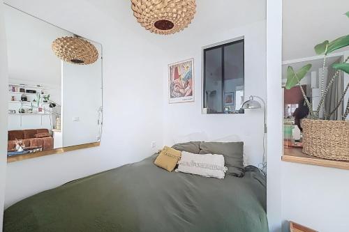 Cette chambre blanche comprend un lit et un miroir. dans l'établissement Elegant apartment near Belleville & Jourdain, à Paris