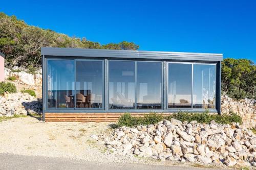 a glass house on the beach with rocks at KastHouse Yellow by Vellaris, Luxury Mobile Home in Mali Lošinj