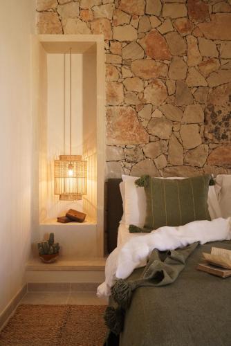 a bedroom with a stone wall with a bed and a lamp at Tenuta Negroamaro in Gallipoli