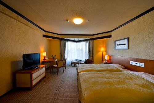 a hotel room with two beds and a television at Hotel Laforet Shuzenji in Izu