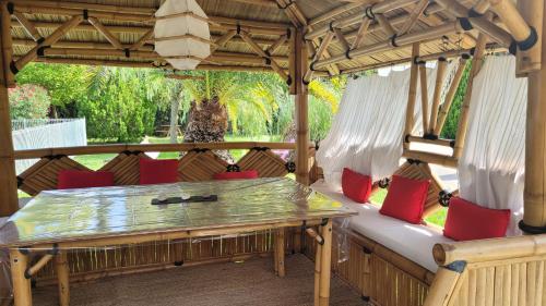 une terrasse couverte avec une table en bois et des chaises rouges dans l'établissement Tropica Nîmes Chalet 2 chambres confort climatisé, à Nîmes