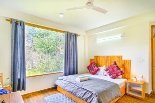 a bedroom with a bed and a large window at The Doors Inn in Manāli