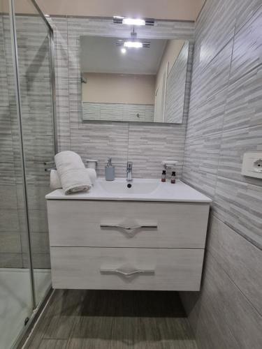 a white bathroom with a sink and a shower at Holiday Home B&M in Pozzallo