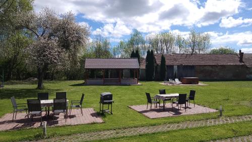 a group of tables and chairs in a yard at Almafás Jakuzzis Vendégház Őrség in Kerkakutas