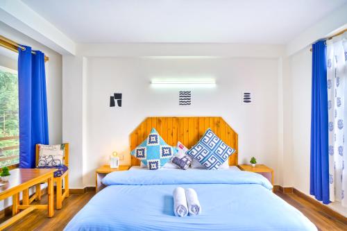 a bedroom with two beds and blue curtains at The Doors Inn in Manāli