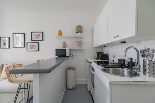 une cuisine blanche avec un évier et un comptoir dans l'établissement Orleans - Paris Neuilly 4Pax, à Neuilly-sur-Seine