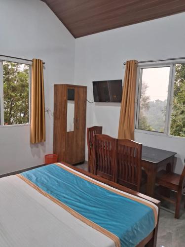 a bedroom with a bed and a table and chairs at Blackcherry Munnar in Munnar