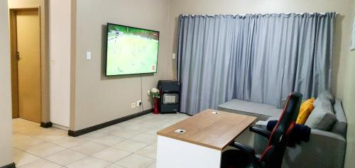 a living room with a tv and a couch and a table at Oasis Home in Midrand
