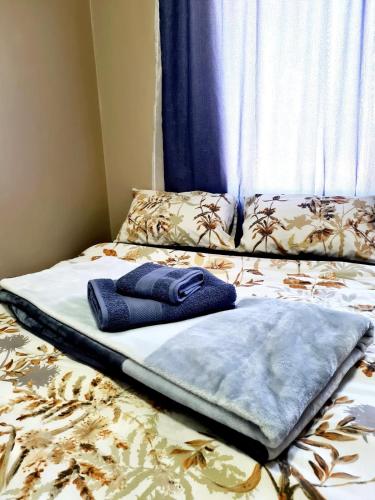 a blanket laying on a bed with a window at Oasis Home in Midrand