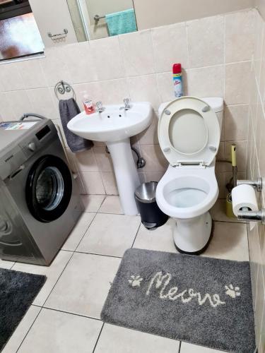 a bathroom with a toilet and a sink and a washing machine at Oasis Home in Midrand