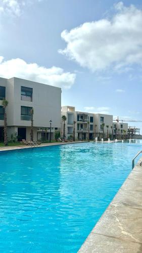 a large blue swimming pool in front of a building at Appartement Sidi Rahal Oceanic in Sidi Rahal