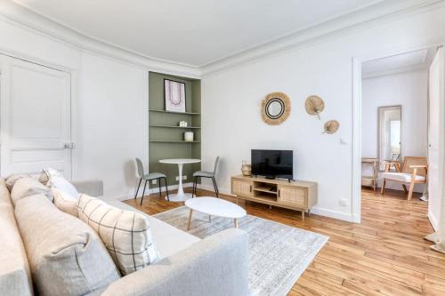 un salon blanc avec un canapé et une table dans l'établissement Delta - Appartement parisien - 9e, à Paris