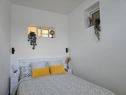 a white bedroom with a bed with yellow pillows at Apartamento Teror Encantado in Teror