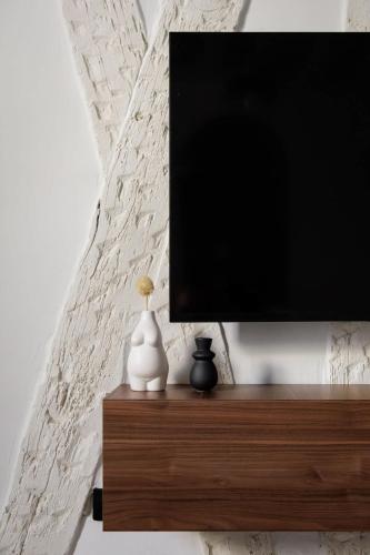 Elle comprend une télévision à écran plat installée au-dessus d'une étagère en bois. dans l'établissement Huchette - Appartement chaleureux Paris, à Paris