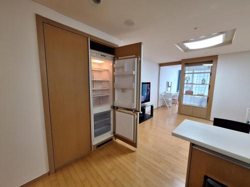 an empty kitchen with an open refrigerator in a room at Stella's Home in Seoul