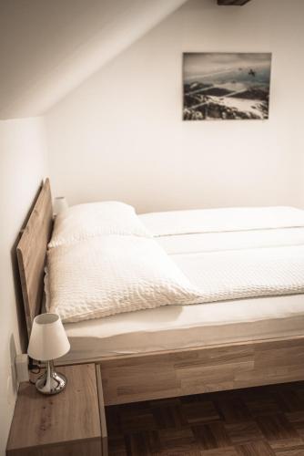 a bed in a white room with a lamp at Haus Dietrich am Red Bull Ring in Spielberg