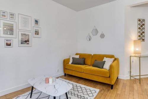 un salon avec un canapé jaune et une table dans l'établissement Poissonniere -Cosy apartment near Montmartre, à Paris