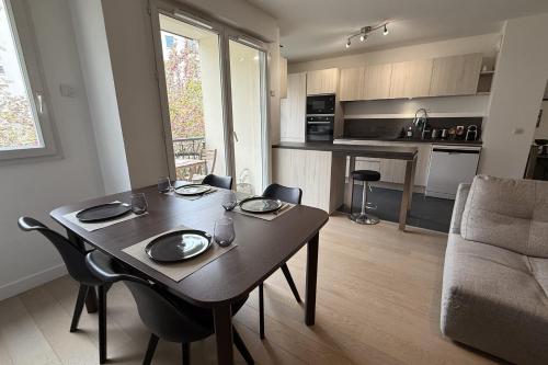 Il comprend un salon avec une table en bois et une cuisine. dans l'établissement 2-bedroom apartment - near park, à Issy-les-Moulineaux
