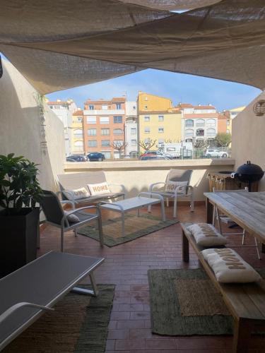 un patio avec des chaises et des tables sur un toit dans l'établissement Studio entièrement rénové avec grande terrasse pour 4 personnes - Cap d'agde, au Cap d'Agde