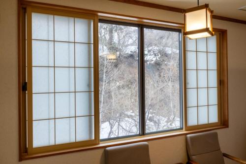 a window in a room with two chairs in front at Fujisan Ryokan in Hanamaki