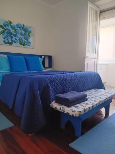 a bedroom with a blue bed with blue sheets and a bench at City's Heart Guesthouse in Ponta Delgada