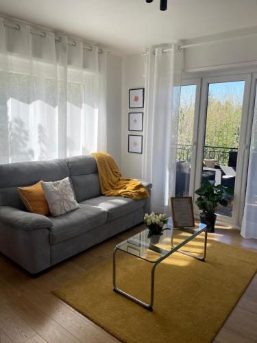 un salon avec un canapé et une table en verre dans l'établissement Grand appartement aux portes de Strasbourg, à Ittenheim