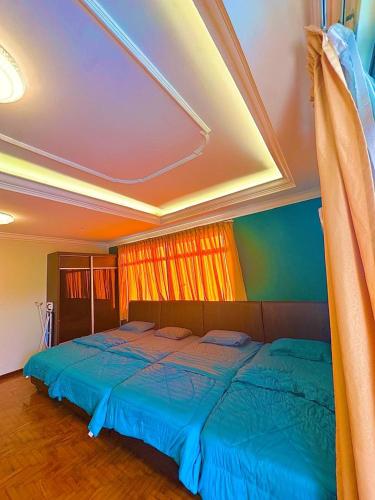 a bedroom with two beds with blue sheets and a window at Emerald Villa in Pasir Gudang