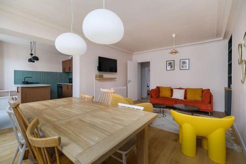 une salle à manger et un salon avec une table en bois et des chaises jaunes dans l'établissement 8 Joubert - 3BDR Galeries Lafayette, à Paris
