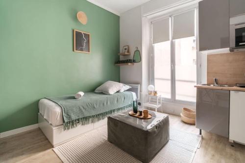 - une chambre avec des murs verts, un lit et une table dans l'établissement 11 Joubert - Joli studio 1PAX Galeries Lafayette, à Paris
