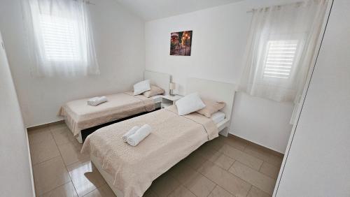 two beds in a small room with windows at Apartments Šolta in Rogač