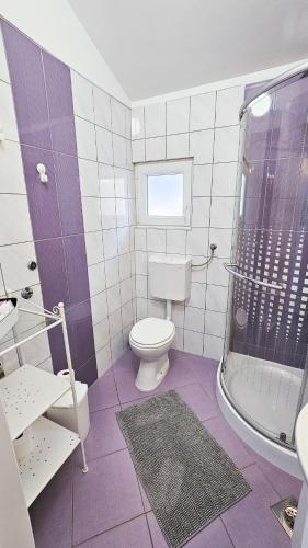 a purple and white bathroom with a toilet and a shower at Apartments Šolta in Rogač