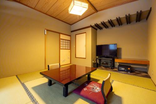 a living room with a table and a flat screen tv at Fujisan Ryokan in Hanamaki