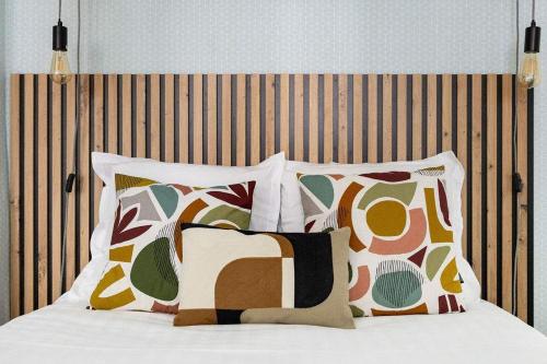 - un lit avec quatre oreillers et une tête de lit en bois dans l'établissement Greneta - Spacious Flat Montorgueuil 4PAX, à Paris