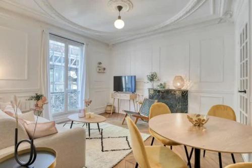 un salon avec des tables, des chaises et une télévision dans l'établissement Chapelle - Appartement familial au centre de Paris, à Paris