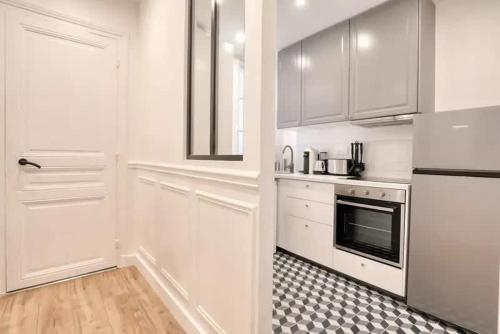 une cuisine avec des armoires blanches et une cuisinière dans l'établissement Chapelle - Appartement familial au centre de Paris, à Paris