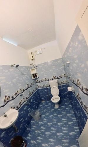 a bathroom with a blue floor with birds on the walls at Point Break Varkala in Varkala