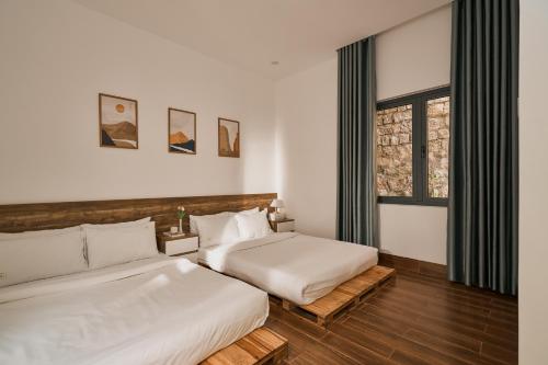 a bedroom with two beds and a window at Nhà Nhím in Da Lat