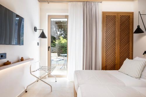 a bedroom with a white bed and a glass chair at Aegean Houses in Kos Town