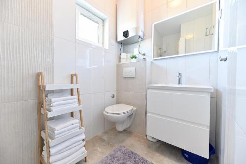 a white bathroom with a sink and a toilet at Apartments Martom 1 in Seline