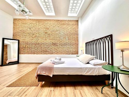 een slaapkamer met een bed en een bakstenen muur bij Mediterranean Apartament in Valencia