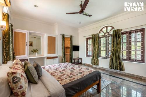 a bedroom with a bed and a ceiling fan at StayVista at Lakshmipuram Palace with Pool,WiFi in Kottayam