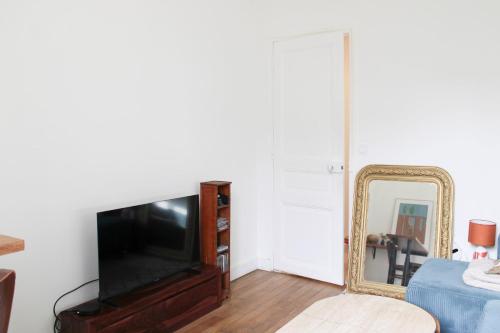 - un salon avec une télévision à écran plat et un miroir dans l'établissement Renovated apartment for 4 people, à Pantin