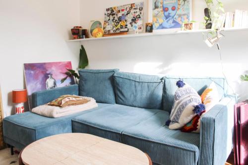un canapé bleu dans un salon avec une table dans l'établissement Renovated apartment for 4 people, à Pantin