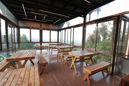 een kamer met houten tafels, banken en ramen bij Misty Bush Munnar in Munnar