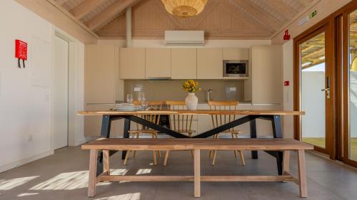 a kitchen with a wooden table and a bench at Pestana Comporta Village Residences in Comporta