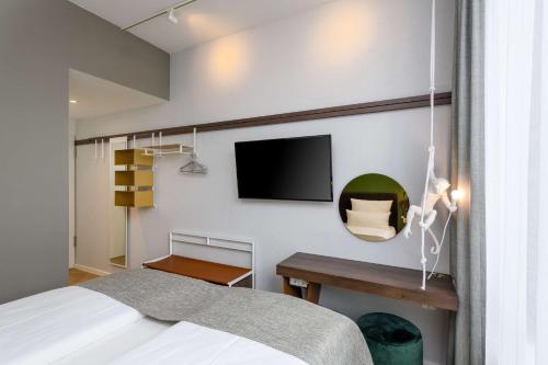 a bedroom with a bed and a tv on the wall at Flightgate Munich Airport Hotel, a member of Radisson Individuals in Hallbergmoos