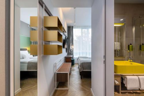 a room with a bathroom with a tub and a bedroom at Flightgate Munich Airport Hotel, a member of Radisson Individuals in Hallbergmoos
